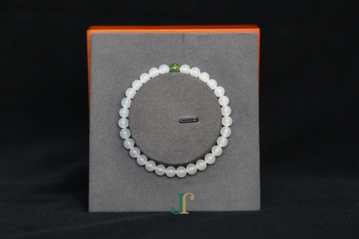 GAIA Earthy 6 Spiritual · Suet White · Green Nephrite — nephrite jade bead bracelet, on a display stand