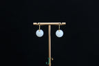 GAIA Luna 14 · Suet White — nephrite jade earrings, on a display stand