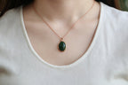 GALET 010 · Spinach Green — nephrite jade pendant, on the hand