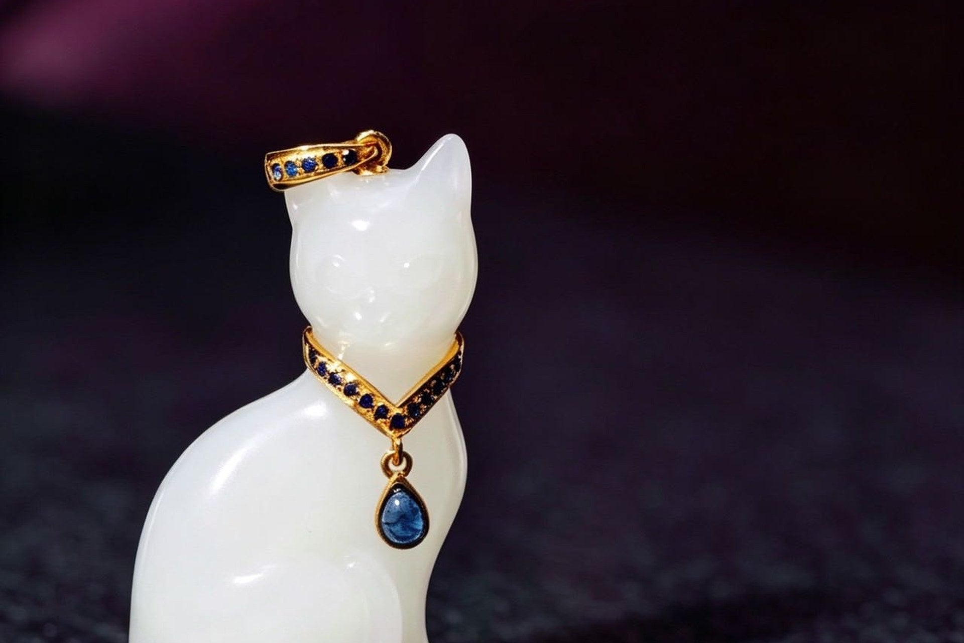 White seated cat pendant with a gold-coloured bail and collar